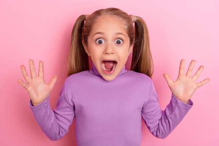 Photo of young pretty cute little girl playing hide and seek with friends in kindergarten isolated on pink color backgroundの写真素材