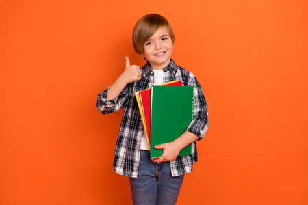 Photo of young boy show finger thumb-up recommend select perfect isolated over orange color...