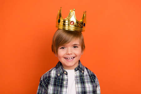 Photo of young cheerful boy have fun wear golden crown party festive isolated over orange color backgroundの写真素材