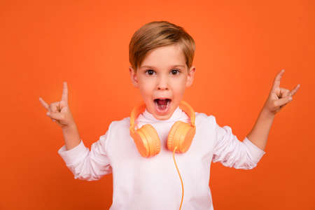 Photo of adorable boy kid making horned symbol listen rock punk melody isolated bright color backgroundの写真素材