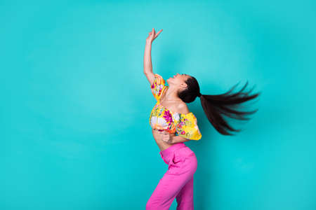 Photo of cute charming girl dressed cropped top wind blowing hair flying pointing up empty space isolated teal color backgroundの写真素材