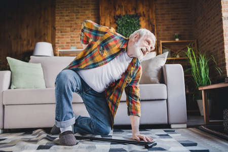 Photo of upset depressed man pensioner wear checkered shirt falling floor sofa osteoporosis indoors house roomの写真素材