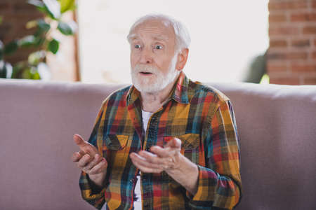 Photo of impressed shocked retired man dressed plaid shirt heard bad news puzzled indoors apartment
