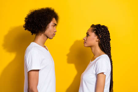 Profile photo of two calm concentrated people look each other isolated on yellow color background