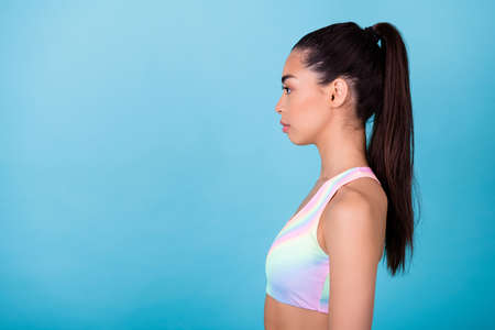 Profile side photo of pretty cute young woman dressed sport bra looking empty space isolated blue color backgroundの写真素材