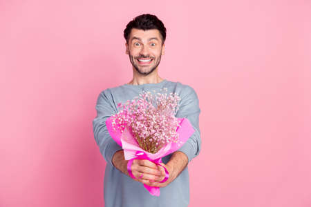 Photo of cheerful excited man hands hold give you flowers bouquet isolated on pink color backgroundの写真素材