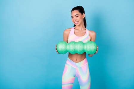 Photo of healthy lady hold massage roll doing crossfit wear rainbow print top leggings isolated blue color backgroundの写真素材