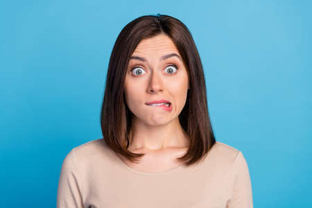 Photo of pretty worried person biting lips stare speechless isolated on blue color backgroundの写真素材