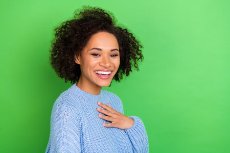 Photo of adorable gorgeous nice woman with perming hairstyle wear blue pullover hold hand on chest isolated on green color backgroundの写真素材