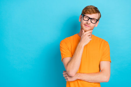 Photo of ginger guy look up wear orange t-shirt eyewear isolated on blue color background