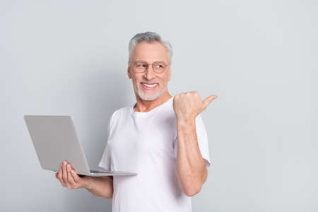 Photo of cheerful man look direct finger empty space offer novelty isolated on grey color backgroundの写真素材