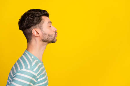 Profile photo of romantic guy kiss promo wear striped t-shirt isolated on yellow color backgroundの写真素材