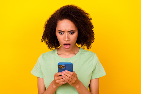 Photo of shocked stupor lady wear green t-shirt chatting modern gadget isolated yellow color...
