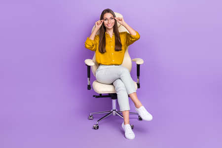 Full size photo of pretty charming girl sit chair hands touch adjust eyewear isolated on violet color backgroundの写真素材