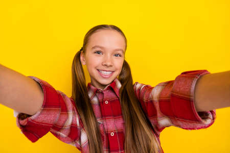 Photo of excited sweet schoolkid dressed plaid shirt tacking selfie smiling isolated yellow color...