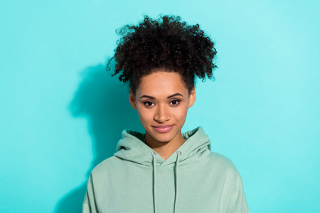 Photo of satisfied glad young person curly hairstyle calm smile look camera isolated on teal color backgroundの写真素材