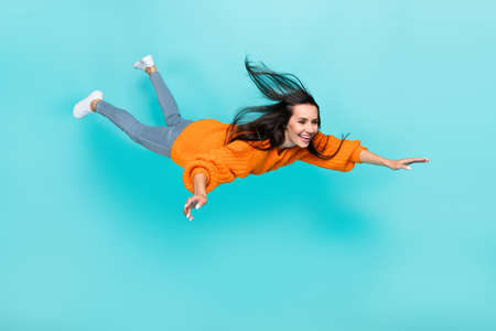 Full length photo of pretty satisfied person fly falling toothy smile isolated on teal color backgroundの写真素材