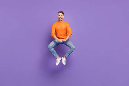 Full size photo of rejoice laughing male jumping in funny pose fooling around isolated on purple color backgroundの写真素材