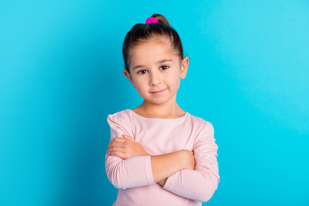 Photo of charming lovely person crossed arms calm face look camera isolated on blue color backgroundの写真素材