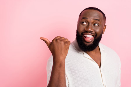 Photo of amazed excited man look direct thumb empty space promo isolated on pink color backgroundの写真素材