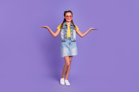 Full size photo of funny school blond girl hold promo wear eyewear t-shirt jeans vest skirt shoes isolated on violet color backgroundの写真素材