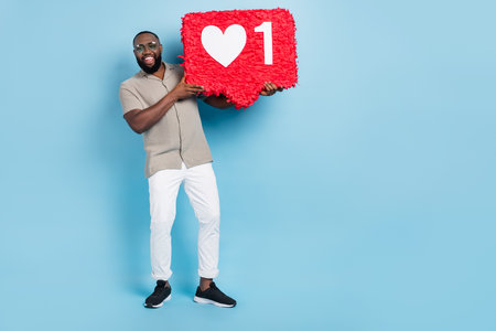 Full body photo of cheerful young guy hold large like collage empty space blank isolated on blue...