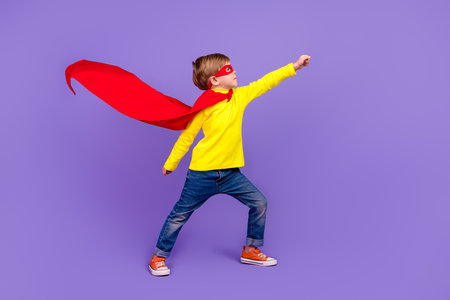 Full length photo of funky cool small son wear red mantle wind blowing rising fist isolated violet color backgroundの写真素材