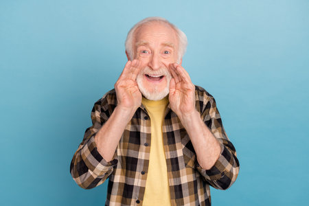 Photo of sweet excited man pensioner dressed checkered shirt arms mouth telling secret isolated blue...