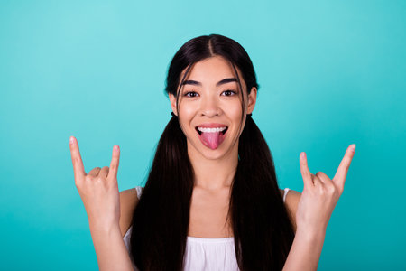 Photo of excited careless thai person hands fingers demonstrate heavy metal symbol tongue out...