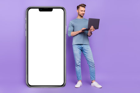 Photo of serious busy guy dressed grey shirt typing modern gadget empty space isolated purple color...