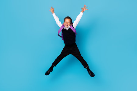 Full body portrait of overjoyed carefree boy jumping raise hands make star figure isolated on blue color backgroundの写真素材