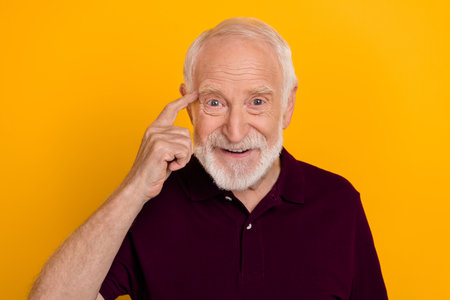 Photo of mature cheerful man finger touch head think clever memory isolated over yellow color...