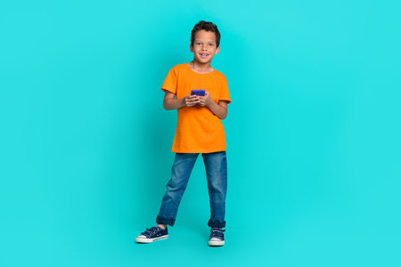 Full length photo of cute boy trendy orange clothes hand hold modern device gadget telephone...