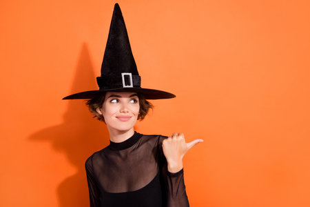 Photo portrait of charming young girl offer look empty space promo dressed trendy black halloween...