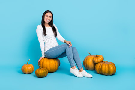 Full body profile side photo of young girl sit pumpkin big harvest healthy isolated over blue color backgroundの写真素材