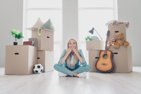Photo of shiny cheerful young lady dressed denim shirt legs crossed relocating new place indoors...