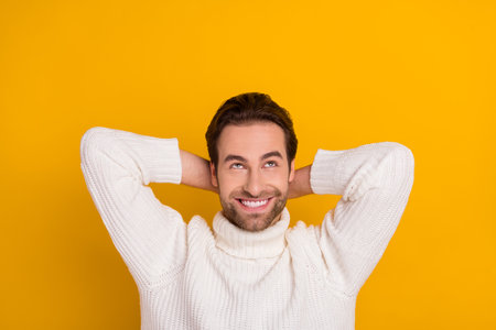 Photo of thoughtful pretty guy dressed white sweater arms behind head empty space isolated yellow color backgroundの写真素材
