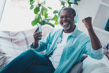 Photo of overjoyed ecstatic guy raise fists in victory triumph watching online stream happy to see...