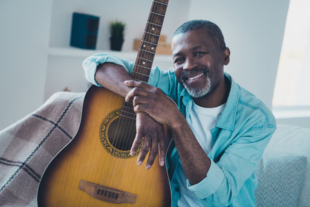 Photo of positive kind friendly mature male hug acoustic guitar playing romantic songs spend free time practicingの写真素材