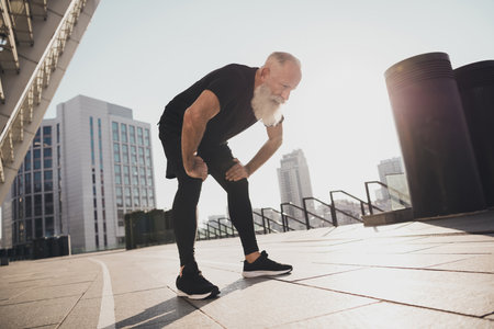 Photo of tired exhausted sportive pensioner man take break catch heavy breath sunset training urban town outdoorsの写真素材