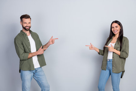 Portrait of attractive cheerful couple demonstrating copy space advert look idea isolated over grey pastel color backgroundの写真素材
