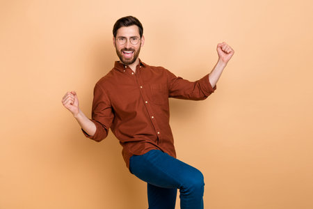 Portrait of overjoyed cheerful person raise fists celebrate achievement isolated on beige color backgroundの写真素材