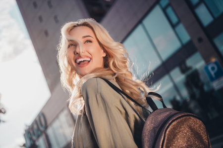 Profile side view portrait of attractive cheerful blond haired girl strolling enjoying sun light good mood traveling outsideの写真素材