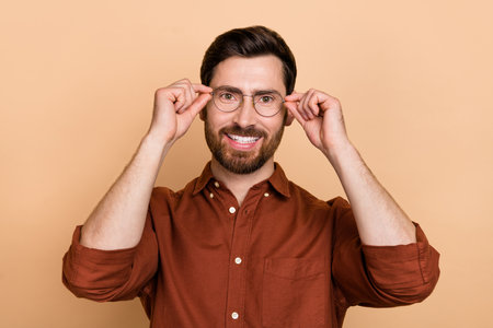 Portrait of positive satisfied person hands touch glasses toothy beaming smile isolated on beige color backgroundの写真素材