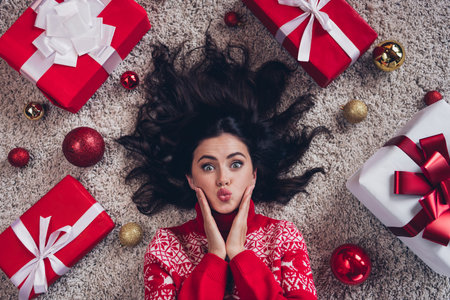 Above view photo of attractive funny lady laying floor pouted lips arms touch cheekbones christmastime house indoorsの写真素材