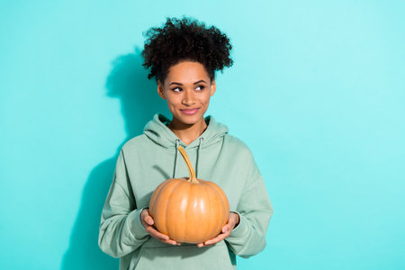 Photo of pretty minded lady hands hold pumpkin look empty space imagine isolated on vivid emerald color backgroundの写真素材