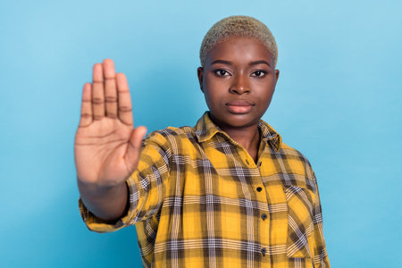 Photo of adorable confident lady wear checkered shirt showing palm refuse you come isolated blue color backgroundの写真素材