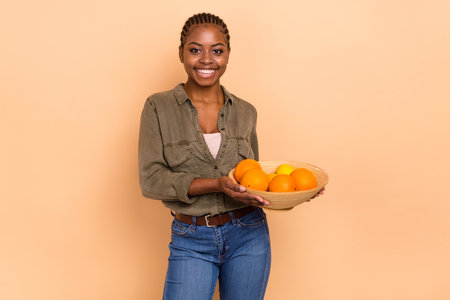 Photo of cheerful person hands hold oranges bowl have good mood isolated on beige color backgroundの写真素材