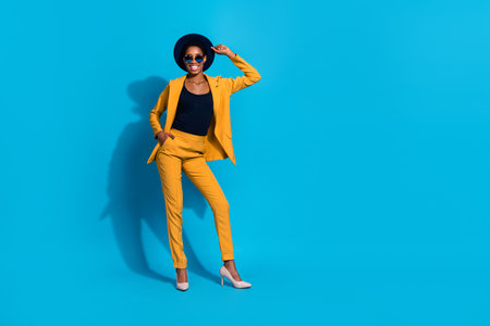 Full body photo of young cheerful man woman wear modern outfit headwear isolated over blue color backgroundの写真素材