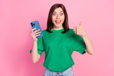 Photo of funny positive lady hold telephone demonstrate thumb up feedback isolated on pink color...
